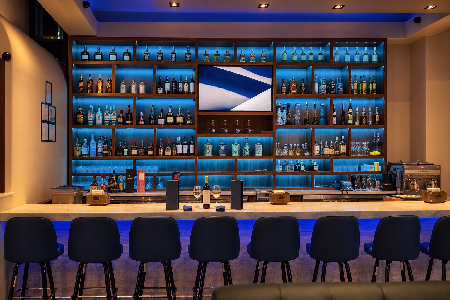The bar at Azul: backlit shelves of tequila, mezcal and spirits above a pale stone bar top lined with navy stools